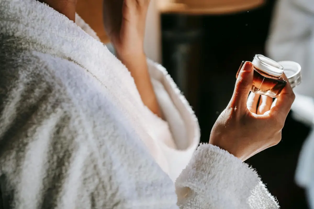 Person in bathrobe thoughtfully holding a skincare product representing informed consumer choices beyond organic marketing claims