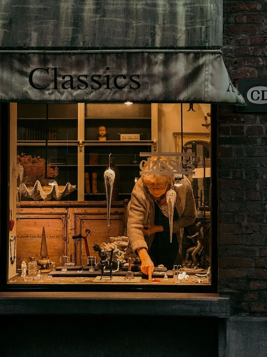 Woman arranging pieces in a European independent jewellery shop window, representing local brand discovery
