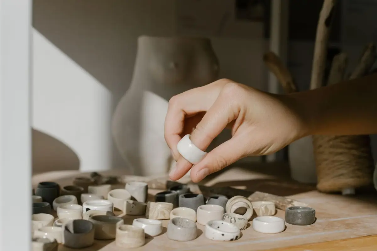 Hand carefully selecting a handmade ceramic ring representing the quality curation criteria behind the Euspree brand directory