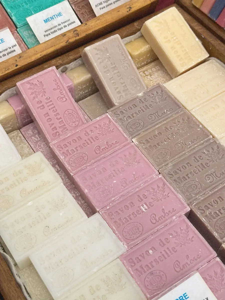 Savon de Marseille bars with embossed Bio Olive stamp at a French market, representing centuries-old French soap-making craft