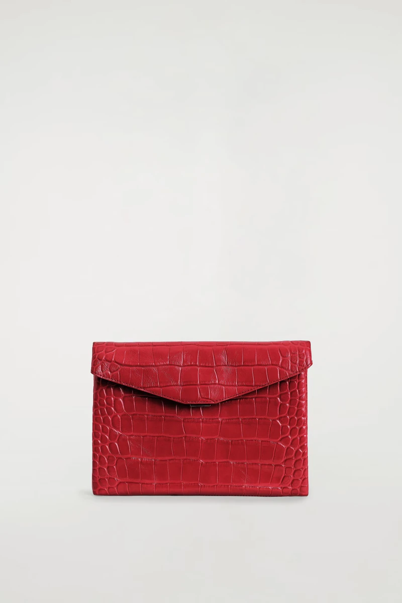 Red croc-effect leather COS envelope clasp pouch against its original studio background
