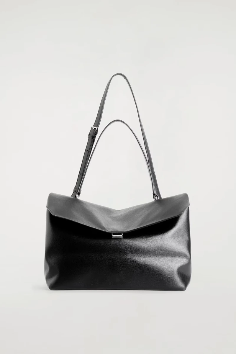 Black leather COS Trullo flap bag against its original studio background