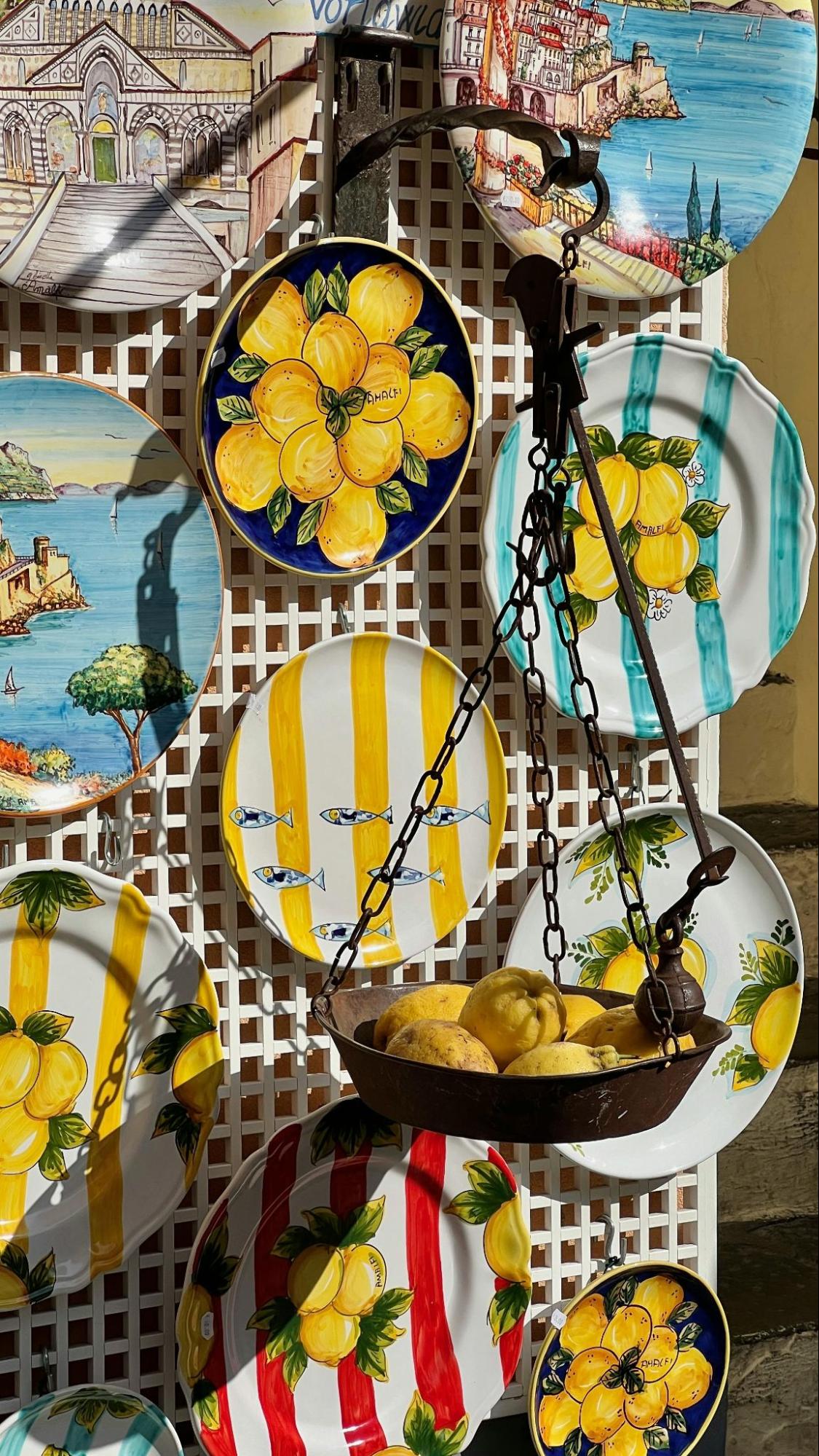 Colorful hand-painted ceramic plates with lemon motifs displayed at an Amalfi Coast market stall, showcasing European craftsmanship and local identity